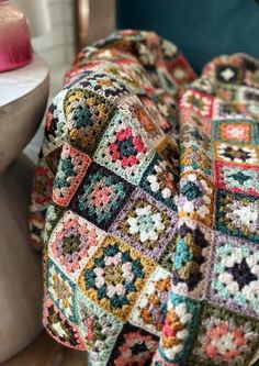 a multicolored crocheted blanket sitting on top of a chair