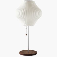 a white lamp on a wooden base with a light bulb attached to it's side