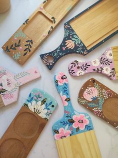 wooden utensils and spoons are laid out on a white counter top with floral designs