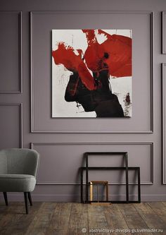 an abstract painting hangs on the wall above a chair in a room with gray walls