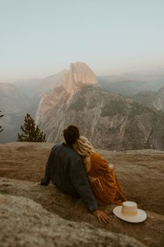 a man and woman sitting on top of a mountain