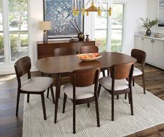 a dining room table with chairs and a bowl of fruit on it