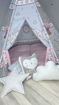 a child's teepee tent with pillows on the floor