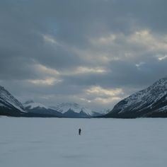 a lone person standing in the middle of a large body of water with mountains in the background