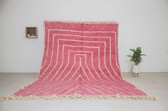 a pink and white rug sitting on top of a floor next to a potted plant