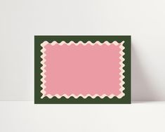 a pink and green square with scalloped edges on a white surface, against a plain background