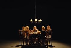 four women sitting at a table in the middle of a dark room with chandelier