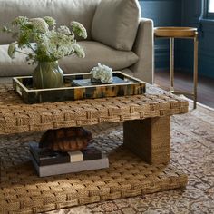 a living room with a couch, coffee table and flowers in a vase on top