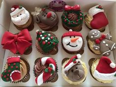 twelve decorated cupcakes in a box with santa hats, snowmen and christmas decorations