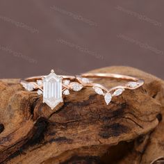 an engagement ring with leaves on it and a white diamond in the center, sitting on top of a piece of wood