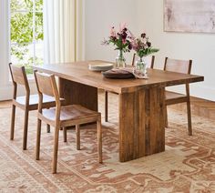 a dining room table with chairs and flowers in vases on the centerpiece next to it