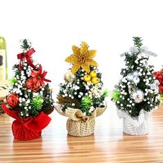 three small christmas trees sitting on top of a wooden table