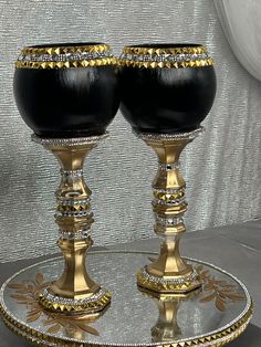 two black and gold goblets sitting on a plate