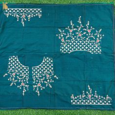 three pieces of blue cloth with white embroidered designs on the top and bottom, sitting on green grass