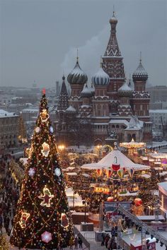 the christmas tree is lit up in front of an ornate building with many lights on it