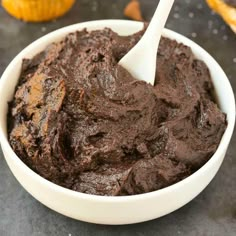 a white bowl filled with brownie batter on top of a black counter next to orange peels