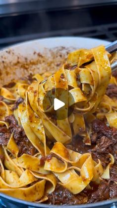 pasta being cooked in a skillet with a ladle full of meat and cheese