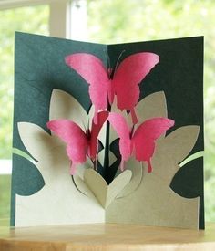 an open card with pink flowers in the center on a table next to a window