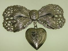 IT HAS BEEN WORN, IS IN NICE CONDITION AND GOOD WORKING ORDER! WITH HEART LOCKET! FAUX SILVER FILIGREE BOW PIN. Vintage Metal Brooches For Gift, Silver Heart Brooches For Gift, Vintage Silver Brooches For Vintage Events, Vintage Antique Silver Heart Jewelry, Victorian Antique Silver Brooch For Gift, Silver Retro Brooches For Gift, Silver Vintage Brooches For Events, Victorian Antique Silver Brooches As Gift, Victorian Antique Silver Brooch