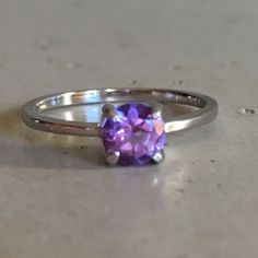 "A TINY round-shape faceted genuine Purple Amethyst hand set in a 4-prong setting featuring a tapered sterling silver shank. This beauty makes a great birthstone ring for those February Birthday gals or a lovely stackable ring for her! Wrapped in a box ready for gift-giving. (r-egt-146) Ring info ------------------------- Genuine Purple Amethyst measures 5mm Sterling Silver *Follow us @belesasjewelry on Instagram for promotions/giveaways *LIKE* us on Facebook http://www.facebook.com/Belesas to f Faceted Sapphire Promise Ring, Faceted Sapphire Fine Jewelry Ring, Faceted Sapphire Ring Fine Jewelry, Classic Amethyst Round Band Ring, Classic Amethyst Ring With Round Cut, Classic Purple Round Band Ring, Classic Amethyst Round Cut Birthstone Ring, Classic Amethyst Birthstone Ring With Round Cut, Fine Jewelry Amethyst Solitaire Ring