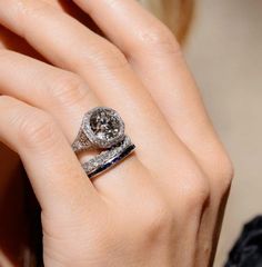 a close up of a person's hand with a ring on their finger and an engagement ring in the other hand