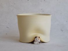 a white ceramic cup with a small figurine in the corner next to it