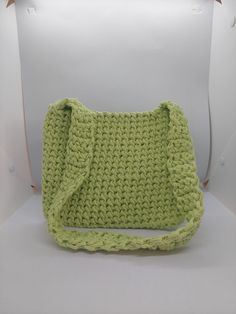 a green crocheted purse sitting on top of a white chair