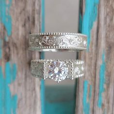 two silver rings with diamonds on them sitting next to a blue door and wooden planks