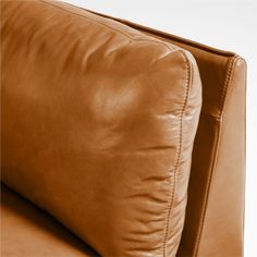 a brown leather couch with two pillows on top of it's headrests