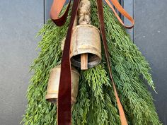 an old bell hanging from a tree with a brown ribbon around it's neck