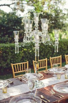 a table set with plates, glasses and silverware for an outdoor dinner party or celebration