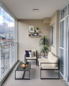 a balcony with two chairs and a coffee table on it, overlooking the city skyline