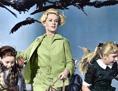 two women walking down the street with birds in the sky behind them and one woman carrying a handbag