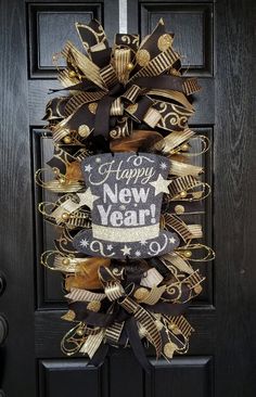 a black and gold new year's wreath hanging on a door with the words happy new year written on it