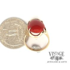 This modern 14 karat yellow gold design holds an oval cabochon of increasingly rare red coral. The natural coral has a vibrant red color with little to no mottling. The coral displays even color with slight growth lines near a prong. The ring is a semi free form design with the mounting offering support to the coral. The stone is secured with 4 prongs and is size 7. Red Cabochon Ruby Ring In 14k Gold, 14k Gold Red Cabochon Ruby Ring, Red Domed Gemstone Rings, 14k Gold Cabochon Red Ring, 14k Gold Red Cabochon Ring, 14k Gold Rings With Red Cabochon, Oval Cabochon Red Ruby Ring In 14k Gold, Red Ruby Oval Cabochon Ring In 14k Gold, Yellow Gold Carnelian Oval Cabochon Ring