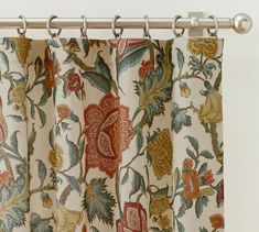 the curtain is hanging in front of an open window with floral print on it and silver rod ends