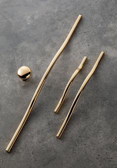 three gold toothbrushes and two spoons on a gray surface next to each other