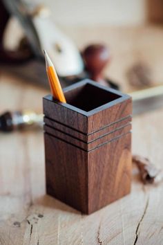 a wooden box with a pencil in it sitting on a table next to some other items