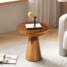 a small wooden table with a book on it and a figurine sitting on top