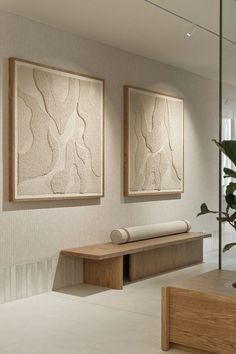 two paintings hang on the wall next to a plant in a room with white walls