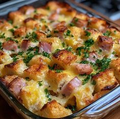 a casserole dish with ham, cheese and parsley in it on a wooden table