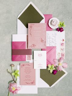 the wedding stationery is laid out on top of each other, including pink and green flowers