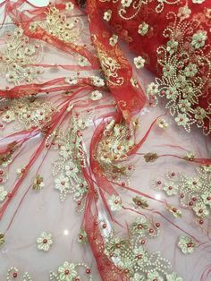 a red and white dress with beading on the bottom, along with sheer fabric