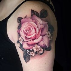 a woman's arm with a rose tattoo on the left side of her shoulder