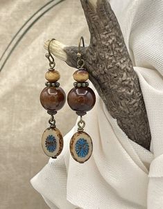 Handmade, unique boho style ceramic earrings. Brown, tan and blue in color. A nice size length at 2-1/8 inches long by .50 inch wide. The round, brown bead is glazed ceramic with a complimenting Czech glass bead at the top. From the bottom hangs a kiwi style Picasso Czech glass bead in blue and tan with a brown Picasso edge. Paired with bronze wires, hooks, and accent beads, these make a perfect casual, rustic style for everyday. They would be great for fall with a sweater and jeans. Give them a Bohemian Brown Round Earrings, Brown Bohemian Round Earrings, Bohemian Brown Beaded Nickel-free Earrings, Bohemian Brown Beaded Round Earrings, Brown Bohemian Earrings With Round Beads, Bohemian Brown Beaded Earrings For Gift, Nickel-free Beige Bohemian Jewelry, Bohemian Beige Beaded Earrings For Gifts, Bohemian Nickel-free Beige Jewelry