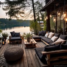 a wooden deck with lots of furniture and lights on it, along with a lake in the background