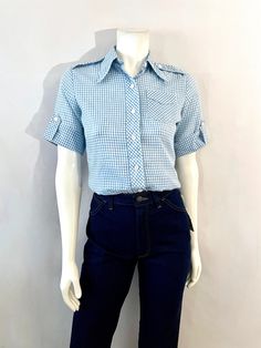 "Vintage 70's Maverick, Checkered, Blouse, Butterfly Collar (S) This Ladies Blouse comes in White Cotton/Polyester blend with a Checkered print in Baby Blue with Half, Cuffed Sleeves with Single Button Closure, Seven front Button Closure and Butterfly Collar. The fabric is light Weight, does not stretch. Cotton/Polyester Blend Made in USA *This Blouse is in Excellent Condition. Size: (S) Modern Day 2 (Tag Size: 32) Bust: 36\" Sleeve Length\" 9\" (outside) 5\" (inside) Length: 25\" Shoulder to Sh Retro Collared Blouse For Work, Plaid Short Sleeve Blouse For Work, 1970s Cotton Short Sleeve Tops, 1970s Style Cotton Short Sleeve Tops, 1970s Style Cotton Tops With Short Sleeves, Vintage Spring Workwear Tops, Vintage Spring Tops For Workwear, Vintage Fitted Plaid Blouse, Fitted Plaid Vintage Blouse