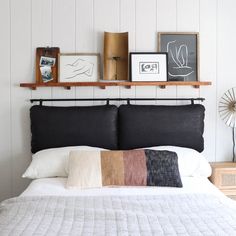 a bed with pillows and pictures on the wall above it, along with other items