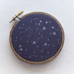 an embroidery project with blue fabric and white stars on it, hanging from a wooden hoop