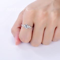 a woman's hand with a diamond ring on top of her finger, against a white background